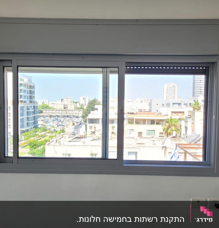 חלון אלומיניום עם נוף עירוני ברקע